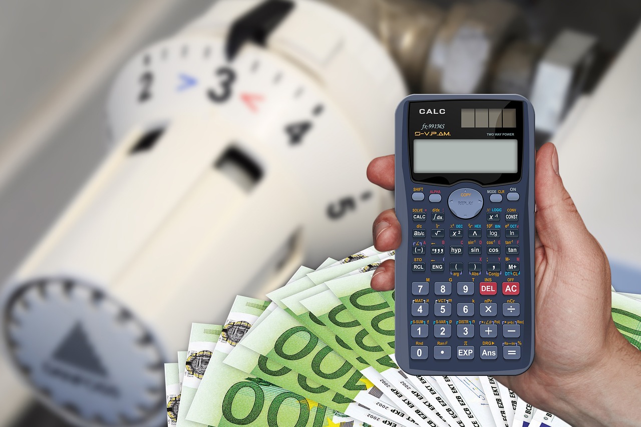 Calcolatrice e banconote in euro davanti a una manopola di riscaldamento, simbolo di risparmio energetico e gestione dei costi di riscaldamento.